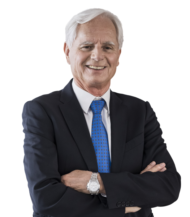 Eine lächelnde Person in einem Anzug und Hemd vor weißem Hintergrund.