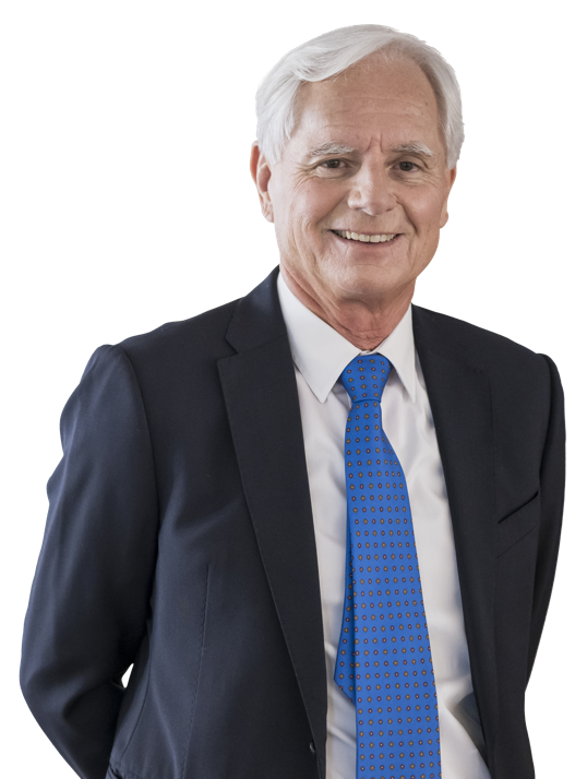 Ein Mann in einem dunklen Anzug mit weißem Hemd und Krawatte lächelt in die Kamera.