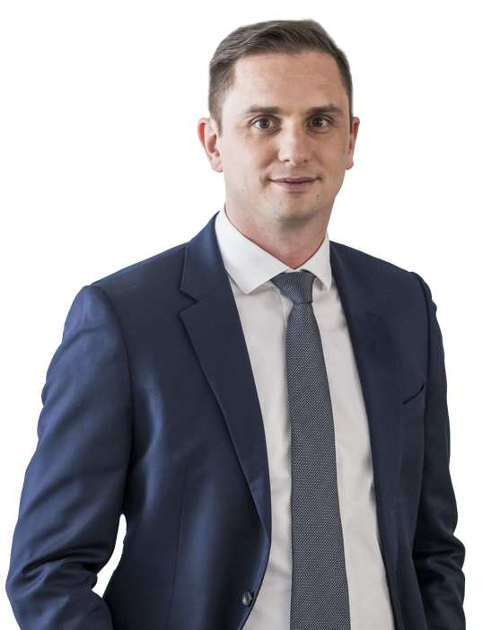 Eine lächelnde Person in einem Anzug und Hemd vor weißem Hintergrund.